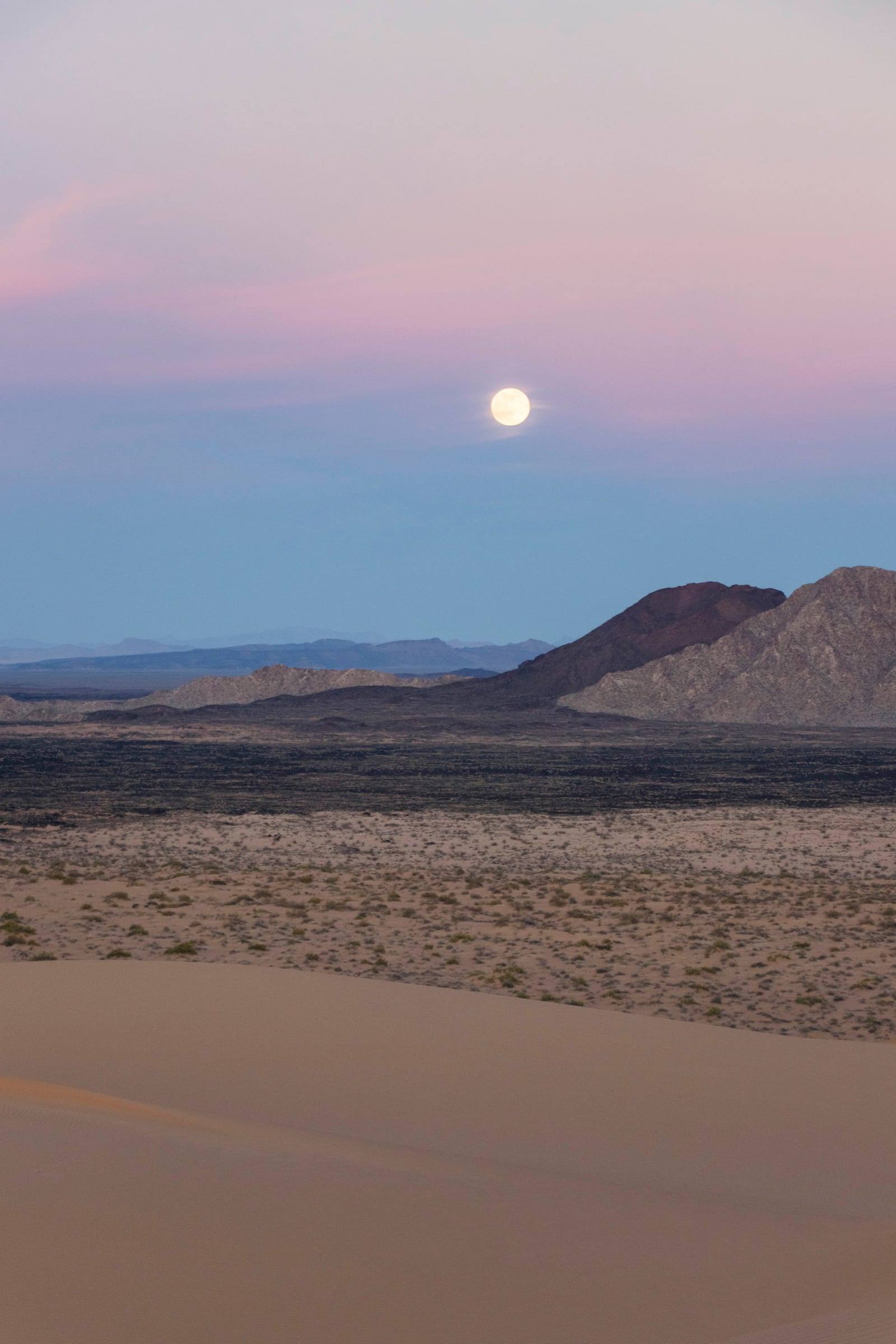 The full moon over the volcanic landscape at dusk